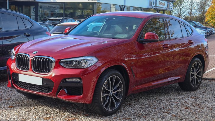 red bmw x4 parked in front of a dealership